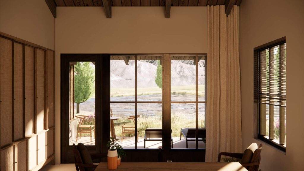 Interior view of a room with large windows and doors opening to a patio, overlooking a river, trees, and mountains in the background.