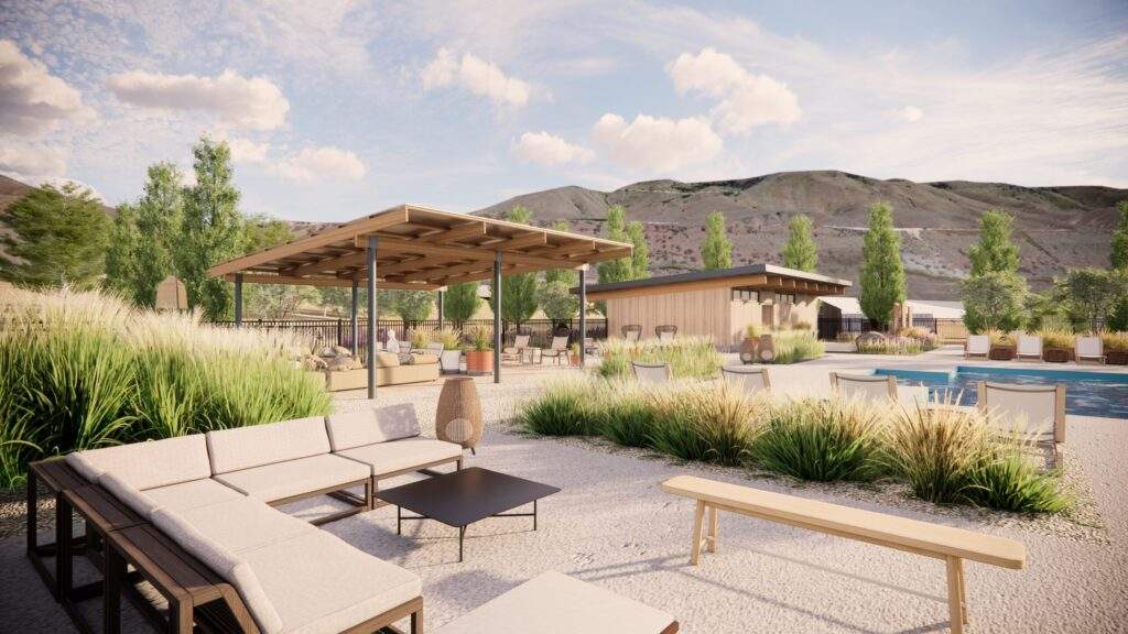 Outdoor lounge area with modern seating, shaded pergola, and landscaping, set against a backdrop of hills and partly cloudy sky, offers stunning vineyard views near Lake Chelan in North Central Washington.