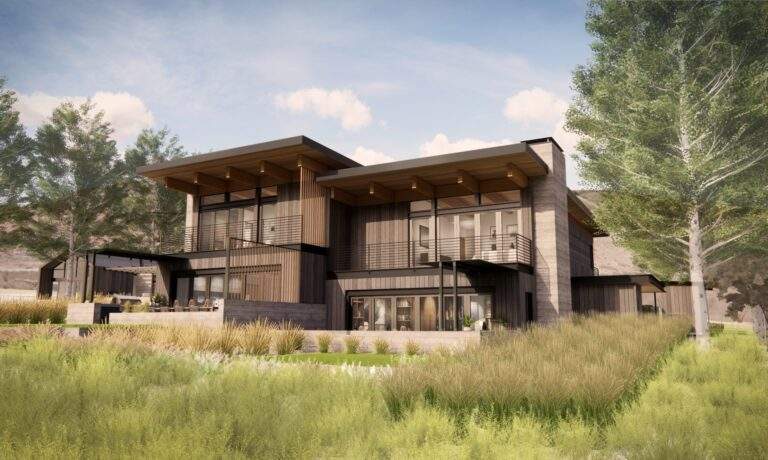 Modern two-story house with large windows, wood and metal accents, sloped roofs, and surrounding landscaped grass and trees under a partly cloudy sky, offering stunning vineyard views at Rocky Pond Estate in North Central Washington.